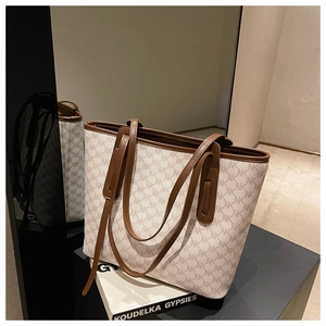 Detail view of large tote bag with brown trim and MK monogram pattern on mirrored surface