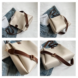 Detail view of large cream tote bag with wide brown nylon strap and gold hardware accents