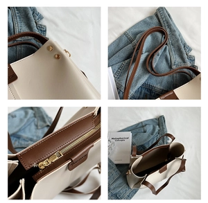 Detailed close-up of contrast stitching, metal rivets, and zipper on the tote bag