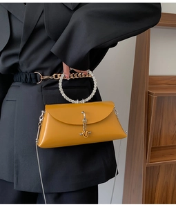 Detail of yellow clutch bag with rhinestone ring handle and silver chain strap