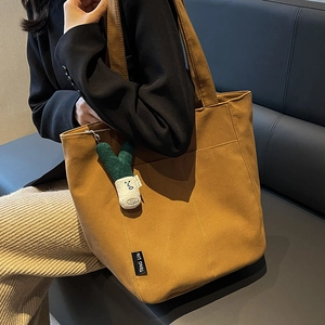 Large canvas tote bag in brown with green plush onion pendant shown on shoulder