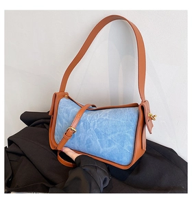 Detailed shot of contrast denim and brown leather stitching on a large shoulder bag
