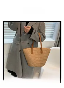 Detail of hand-woven straw tote with premium brown leather handles and textured weave