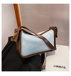 Detail of blue denim and brown leather shoulder bag with elegant gold hardware
