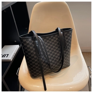 Detailed close-up of large tote bag with NK pattern and slim leather handles on a chair
