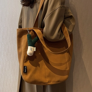 Brown canvas tote bag with large capacity for women featuring a cute plush pendant