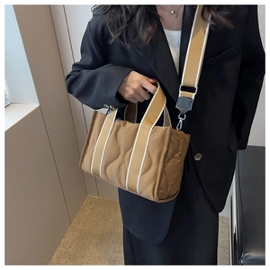 Vista detallada del bolso tote de nailon acolchado marrón con costuras onduladas y asa ancha