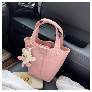 Details der rosa Eimertasche mit Lychee-Struktur und Bärenanhänger auf dem Autositz