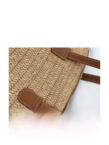 Detailed macro view of the sturdy leather strap stitching on a woven straw tote bag
