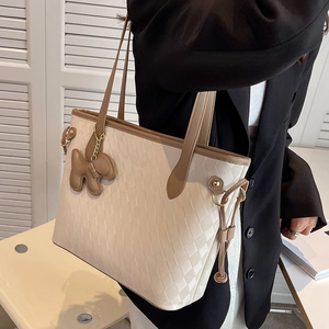 Offwhite gesteppte Shopper Tasche mit braunem Gurt und Anhänger über der Schulter