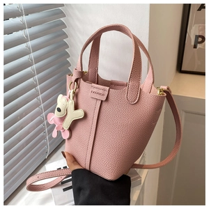 Detail der rosa Bucket-Bag aus genarbtem Leder mit FASHION-Prägung und süßem Anhänger