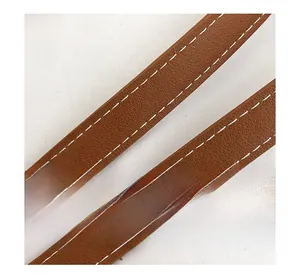 Detail of brown faux leather shoulder straps with contrast white stitching and grainy texture
