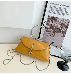 Detail of yellow leather crossbody bag with silver chain and rhinestone round handle