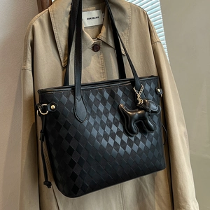 Große schwarze gesteppte Shopper-Tasche mit Hundeanhänger an einem Trenchcoat