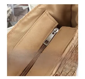 Detail of silver metal zipper and brown fabric lining inside a hand-woven straw bag