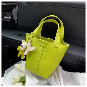 Detail der neongrünen Eimertasche aus Kieselleder mit Anhängern auf dem Autositz