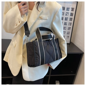 Detalle de bolso tote de nailon acolchado negro con ribetes blancos y correa ancha