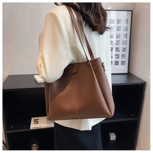 Detailed view of dark brown faux leather tote bag with wide strap and stitching