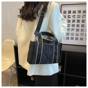 Modelo con bolso tote de nailon acolchado negro con ribete blanco y correa ancha al hombro