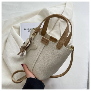 Detail der cremefarbenen Beuteltasche mit Litschi-Textur und braunen Riemen