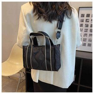 Vista trasera de modelo con bolso tote de nailon acolchado negro y correa ancha