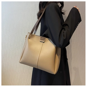 Detail of apricot large tote bag with wide brown straps and embossed logo on black blazer