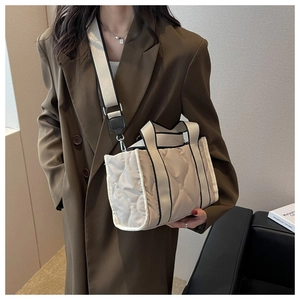 Detalle del bolso tote de nailon acolchado beige con borde negro y correa ancha ajustable