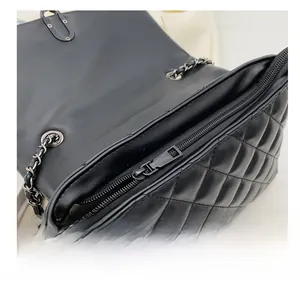 Close-up of black quilted leather bag showing smooth metal zipper and inner compartment