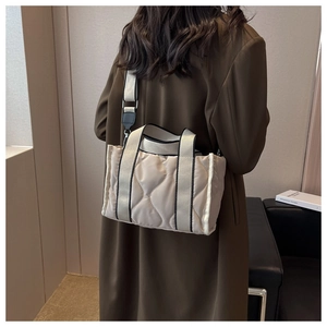 Detalle del bolso tote de nailon acolchado beige con asas tejidas en contraste