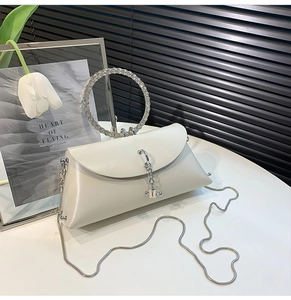 Detail of ivory leather evening bag with rhinestone circular handle and silver snake chain
