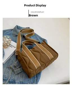 Detalle de bolso tote de nailon acolchado marrón con correa ancha sobre tela vaquera