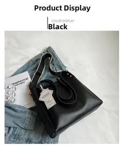 Detail of black leather tote bag with stylish wide woven strap on denim background