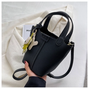 Detail der schwarzen Handtasche aus Leder mit Litschistruktur und modischen Anhängern