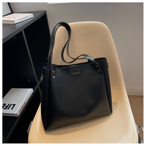 Close-up of minimalist black tote bag with vertical seam and gold rivet on design chair