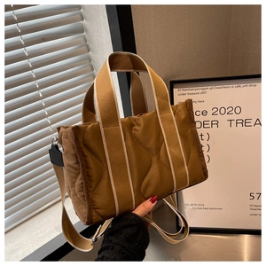 Detalle del bolso tote de nailon acolchado marrón con costuras y asa de rayas