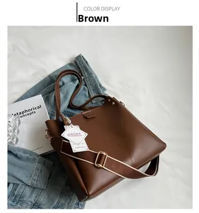 Detail view of large brown tote bag featuring wide fabric strap and matte leather finish