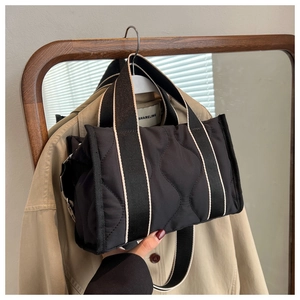Detalle de bolso tote de nailon acolchado negro con correa ancha de borde en contraste plata
