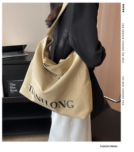 Close-up of a khaki canvas tote bag with black letter print and wide shoulder strap