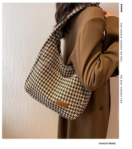 Classic houndstooth woven tote bag with brown leather tag shown on model shoulder