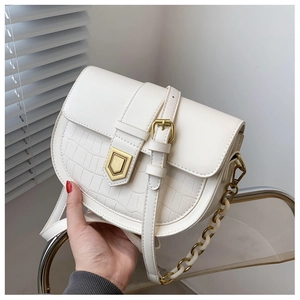 Detail showing white saddle bag with crocodile texture, gold clasp and chain