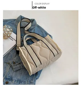 Detalle de bolso tote de nailon acolchado blanco roto con correas a rayas y costuras de onda