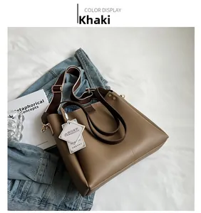 Detail view of khaki leather tote bag with stylish brown and white wide shoulder strap