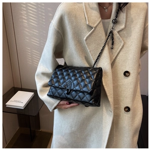 Detail of black quilted leather crossbody bag with chain strap and matte U-shaped lock