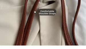 Macro shot of dark brown litchi grain leather strap with precise stitching on tote bag