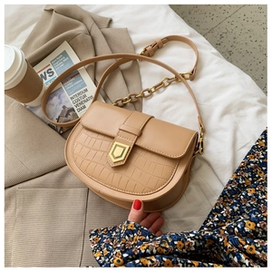 Detail of khaki saddle bag with crocodile texture and gold hexagon buckle decoration