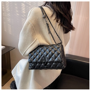 Detail of black quilted leather shoulder bag with metal chain and decorative gold ball
