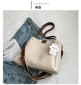 Detail of cream white tote bag with brown trim and wide woven strap on fabric background