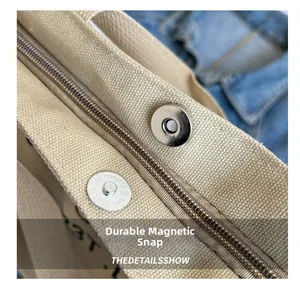 Detailed macro view of sturdy magnetic snap and silver zipper on beige canvas tote bag