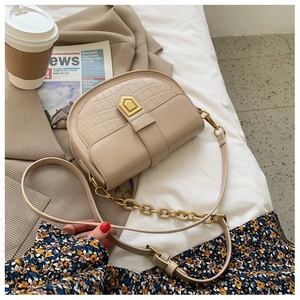 Detail of beige saddle bag with crocodile texture and golden clasp on check blazer
