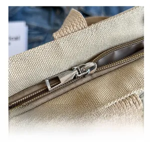 Macro shot of silver metal zipper on textured beige canvas tote bag with smooth detail